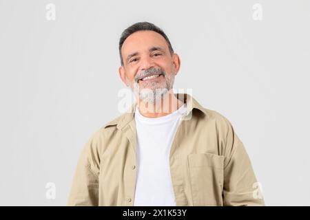 Senior lächelt mit Händen in Taschen auf weißem Hintergrund Stockfoto