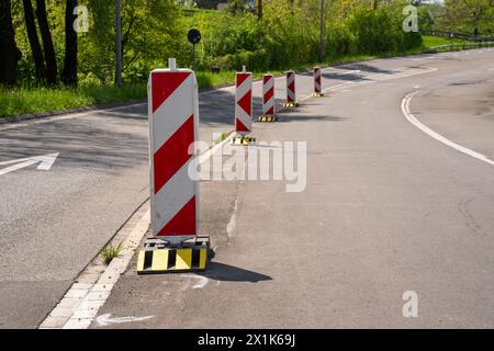 Warnkähne in Rot und Gelb am Straßenrand signalisieren einen Umweg auf einer Baustelle. Stockfoto