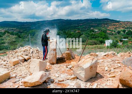 VILLANUEVA, SANTANDER, KOLUMBIEN, 02. APRIL 2024, ÜBERSICHT ÜBER DEN MANN, DER IN EINER HANDWERKSTATT IM FREIEN STEIN MIT EINEM ELEKTRISCHEN POLIERER SCHNEIDET Stockfoto