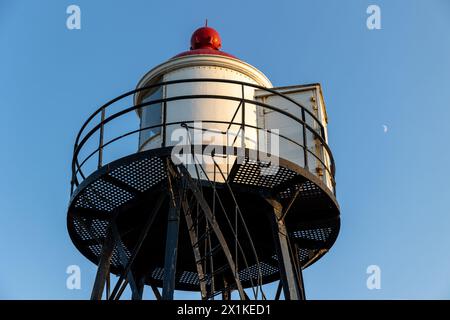 Ein wunderschöner weiß-roter Leuchtturm an der Nordseeküste in den Niederlanden. Leuchtturm gegen den blauen Himmel. Schöne Metallkonstruktion. Stockfoto