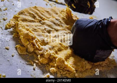 Handwerkliches Kneten von Teig mit Handschuhen, Gegenansicht Stockfoto