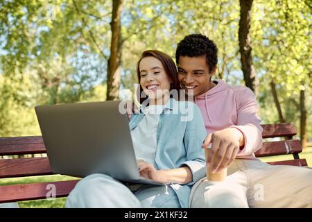 Ein stilvolles Paar, lebhaft gekleidet, in einem Laptop auf einer Parkbank. Stockfoto