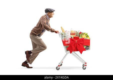 Profilaufnahme eines Rentners in voller Länge, der mit Essen in einem Einkaufswagen auf weißem Hintergrund läuft Stockfoto