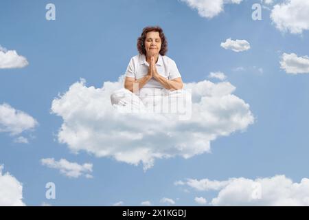 Ältere Frau, die auf einer Wolke sitzt und am Himmel betet Stockfoto