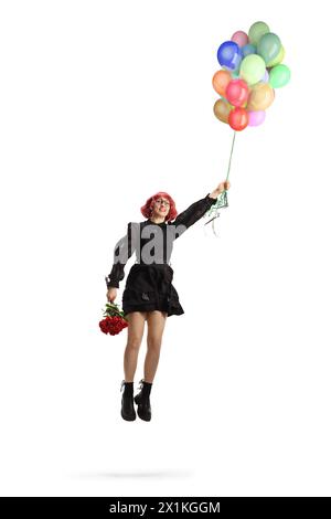 Frau in einem schwarzen Kleid mit roten Rosen, die fliegen und einen Haufen Ballons auf weißem Hintergrund halten Stockfoto