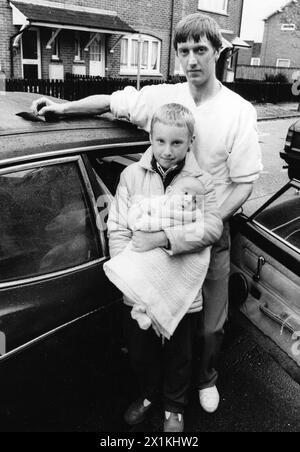 DAVID LEWIS AUS EASTLEIGH MIT SEINEN KINDERN, DAMIEN UND BABY JAMES NEBEN IHREM AUTO, NACHDEM EIN TEIL EINES FLUGZEUGS VOM HIMMEL FIEL UND AUF DEM AUTODACH LANDETE. OKT. 1988 PIC MIKE WALKER 1988 Stockfoto