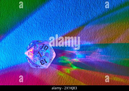 Prismatische D20-Würfel auf strukturiertem Regenbogentuch, Makroansicht Stockfoto