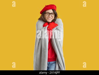 Schöne junge Frau zittert und wärmt sich an kalten Herbsttagen in einer Decke auf Stockfoto