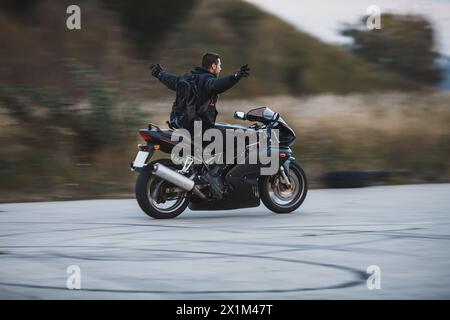 Junge Biker, die ein Sportmotorrad ohne Hände fahren und sich frei fühlen. Freiheitskonzept. Bewegungsunschärfe auf Hintergrund. Stockfoto