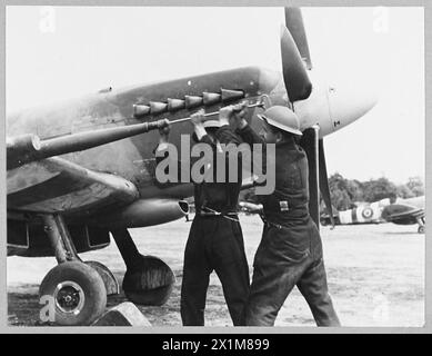 R.A.F. BODENBESATZUNGEN HELFEN BEI DER BEKÄMPFUNG DER FLUGBOMBE - R.A.F. Bodenbesatzungen der Air Defence of Great Britain wurden gründlich getestet, seit die Flugbomben gegen Großbritannien gestartet wurden. Sie haben hart gearbeitet, um die Kampfflugzeuge zu warten, sie zu betanken und neu zu bewaffnen und oft lange Stunden in Anspruch zu nehmen. Viele der Männer arbeiten in Frontstationen und tragen Stahlhelme zum Schutz bei der Wartung des Flugzeugs. Das Bild (Ausgabe 1944) zeigt Eine Bodenbesatzung, die die Kanone eines Kampfflugzeugs, Royal Air Force, reinigt Stockfoto