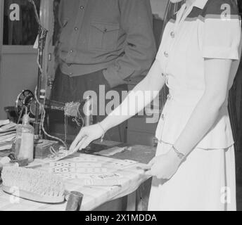 BIRTH OF A STAR: EVERYDAY LIFE FÜR SCHAUSPIELERIN MURIEL PAVLOW, ENGLAND, 1945 – Schauspielerin Muriel Pavlow spielt das Kartenspiel Patience, während sie darauf wartet, dass ihre Szene in den Welwyn Gardens Studios in Hertfordshire genannt wird. Der Garderobenmeister, D A (Bill) Smith, beobachtet sie, wie sie spielt. Stockfoto