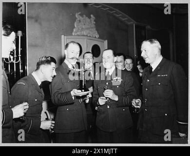 SQUADRON RE-UNION DINNER - Foto ausgestellt 1944. Foto beim Re-union Dinner einer R.A.F. Auxiliary Squadron Shows - Wing Commander B.R.O'B. Hoare, DSO & Bar., DFC & Bar., zeigt einem Mitglied der Staffel ein silbernes Moskitoflugzeug. Der Air Commodore Sir Lindsay Everard, Abgeordneter, Ehrenflugkommodore der Geschwader befindet sich auf der rechten Seite und Group Captiain J.A. Cecil Wright, AFC., TD., Abgeordneter., Gründer der Geschwader ist der zweite von rechts, Royal Air Force Stockfoto