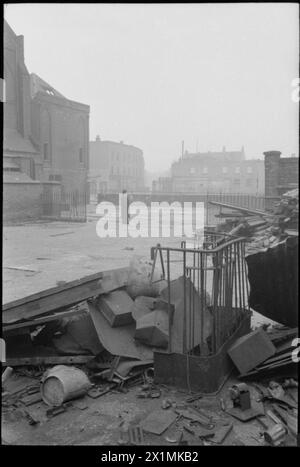 Eine KIRCHE ERHEBT SICH AUS DER ASCHE: BOMBENSCHADEN AN DER St GEORGE's CATHEDRAL, SOUTHWARK, 1942 – Pater Dixon steht an der Stelle der ehemaligen Schule an der St George's Roman Catholic Cathedral, an der Ecke St George's Road und Lambeth Road, Southwark. Die Kathedrale wurde nach einem Brandbombenangriff am 16. April 1941 schwer beschädigt. Trümmer, einschließlich Schutt und alte Geländer, sind im Vordergrund zu sehen. Stockfoto