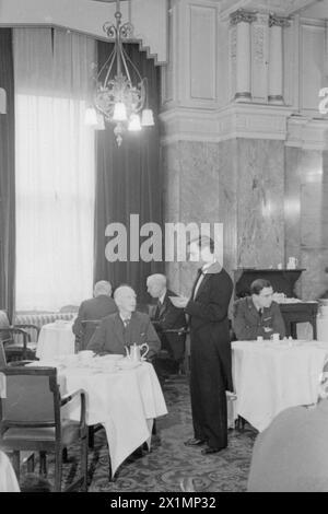 HARRY HARGREAVES GEHT ZUM BUCKINGHAM PALACE: VON YORKSHIRE NACH LONDON, UM SEINE BRITISCHE EMPIRE-MEDAILLE 1943 zu HOLEN - Harry Hargreaves gibt dem Kellner seine Bestellung, während er in der komfortablen und kunstvollen Umgebung seines Hotels frühstückt. Heute ist der Tag, an dem er seine britische Empire-Medaille im Palast abholt. Stockfoto