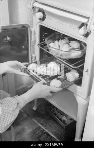 Ein TAG IM LEBEN Einer HAUSFRAU AUS KRIEGSZEITEN: ALLTAG IN LONDON, ENGLAND, 1941 - Mrs Day lässt ihr Abendessen nach einem anstrengenden Tag in den Ofen stellen. Das Lebensmittelministerium ermutigte die Menschen, ihre gesamte Mahlzeit im Ofen zu kochen, um Kraftstoff zu sparen. Stockfoto