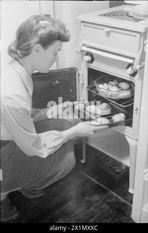 Ein TAG IM LEBEN Einer HAUSFRAU AUS KRIEGSZEITEN: ALLTAG IN LONDON, ENGLAND, 1941 - Mrs Day lässt ihr Abendessen nach einem anstrengenden Tag in den Ofen stellen. Das Lebensmittelministerium ermutigte die Menschen, ihre gesamte Mahlzeit im Ofen zu kochen, um Kraftstoff zu sparen. Stockfoto