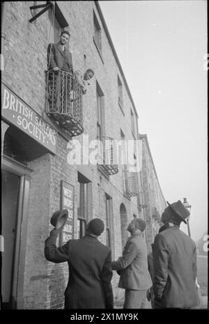 Neuankömmlinge im West Indies Merchant Seamen's Hostel am 14-16 Lovaine Place, Newcastle-upon-Tyne, 1941, winken den Seeleuten auf dem Balkon nahe dem Eingang zu; das Hostel wurde von der British Sailors' Society finanziert. Stockfoto
