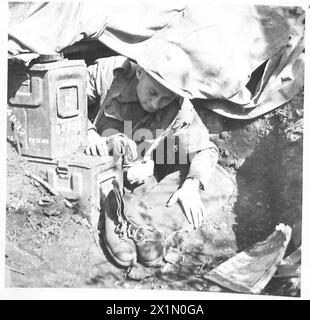 FÜNFTE ARMEE : ANZIO BRIDGEHEADINFANTRY PATROUILLE IM BRÜCKENKOPF (IN DER LINIE REKONSTRUIERT) - Sgt. Trainor holt seine Patrouillenstiefel und Kappendecke heraus. Patrouillenstiefel sind aus Kreppsohlen versehen, die für Ruhe sorgen und auf felsigem Boden einen guten Halt bieten. Anstelle von Stahlhelmen werden Kappendecken getragen, um die Britische Armee besser zu tarnen Stockfoto