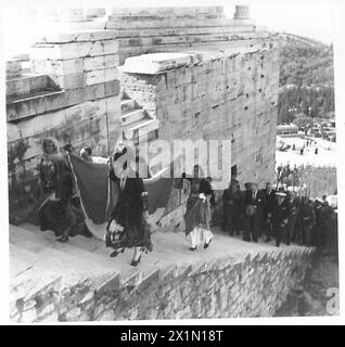 DIE GRIECHISCHE REGIERUNG KEHRT NACH GRIECHENLAND ZURÜCK - griechische Mädchen in Nationalkostümen, die die griechische Flagge tragen, die über dem Parthenon gehisst wird, führen die Prozession die Stufen zur Akropolis, britische Armee Stockfoto