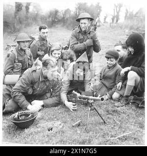 ZEHN MÄNNER FÜR DIE ZWEITE FRONT - einige Dorfkinder zeigen ein lebhaftes Interesse an der Bren-Waffe, die Private Campin einem kleinen Mädchen, der britischen Armee, demonstriert Stockfoto