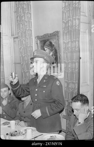 DIE ALLIIERTEN STREITKRÄFTE FEIERN DAS JÜDISCHE NEUJAHR: RELIGIÖSE FEIERN IM BALFOUR SERVICE CLUB, LONDON, Großbritannien, 1943 – Captain Judah Nadich, ein Rabbiner der amerikanischen Armee, hebt sein Glas, während er das Kiddush-Gebet anbietet. Links von Captain Nadich (ursprünglich aus Baltimore, Maryland), versteckt durch seinen rechten Arm, befindet sich Captain Gershon Levi aus Montreal, Kanada, ein Rabbiner der kanadischen Streitkräfte. Er hatte zuvor das Gebet über das Brot geopfert. Rechts auf dem Foto ist Colonel Moses Strock aus Boston, Massachusetts. Stockfoto