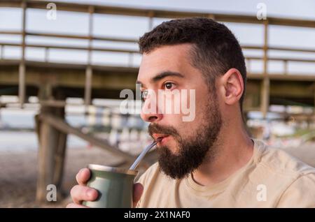 Mann trinkt chimarrão, Mate (eine Infusion von Yerba Mate mit heißem Wasser) bei Sonnenuntergang in uruguay Stockfoto