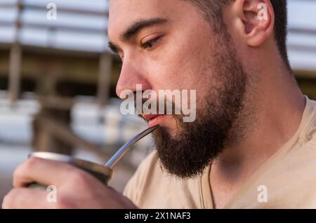 Mann trinkt chimarrão, Mate (eine Infusion von Yerba Mate mit heißem Wasser) bei Sonnenuntergang in uruguay Stockfoto