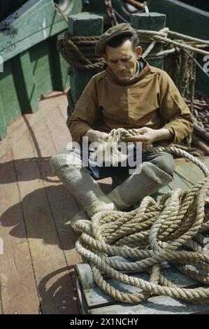 Mr. De Groote, ein belgischer Fischer, wird auf dem Deck eines Fischerbootes in Brixham, Devon gezeigt, wie er zivile Beiträge zu den Kriegsanstrengungen in Großbritannien von 1939 bis 1945 zeigt. Stockfoto