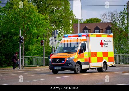 Augsburg, Bayern, Deutschland - 17. April 2024: Ambulanz des Bayerischen Roten Kreuzes fährt mit Blaulicht durch die Stadt zu einem Rettungseinsatz *** Rettungswagen des Bayerischen Roten Kreuzes fährt mit Blaulicht durch die Stadt zu einem Rettungseinsatz Stockfoto