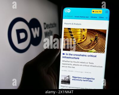 Handybesitzer mit Internetseite der Deutschen Welle (DW) vor dem Logo. Konzentrieren Sie sich auf die Mitte des Telefondisplays. Stockfoto