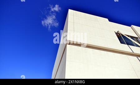 Sonnenlicht und Schatten auf der Oberfläche von weißem Beton Gebäudewand vor blauem Himmel Hintergrund, geometrische Außenarchitektur in Minimal Street Photogra Stockfoto