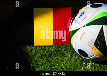 HAMBURG, DEUTSCHLAND, 17. APRIL 2024: Belgische Nationalflagge und offizieller Fußball des Fußballturniers Euro 2024 in Deutschland auf grünem Gras platziert. Bl Stockfoto