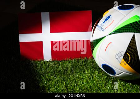 LEIPZIG, DEUTSCHLAND, 17. APRIL 2024: Dänische Nationalflagge und offizieller Fußball des Fußballturniers der Euro 2024 in Deutschland auf grünem Gras platziert. Bl Stockfoto