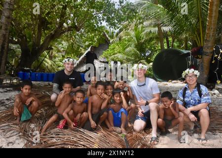 Woleai, Mikronesien, Föderierte Staaten Von. 12. April 2024. Die Crew des Sentinel-Klasse-Schnellreaktionsschneiders USCGC Oliver Henry posiert mit Kindern, nachdem sie Trockenhilfsvorräte, Umkehrosmose-Systeme und Techniker geliefert hat, um die Bewohner der abgelegenen Insel zu unterstützen, am 12. April 2024 in Woleai, Yap State, Föderierte Staaten von Mikronesien. Quelle: CWO Sara Muir/USCG/Alamy Live News Stockfoto