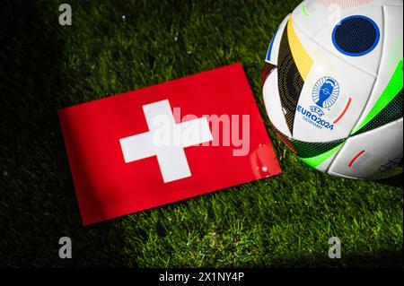 LEIPZIG, DEUTSCHLAND, 17. APRIL 2024: Schweizer Nationalflagge und offizieller Fußball des Fußballturniers Euro 2024 in Deutschland auf grünem Gras platziert Stockfoto