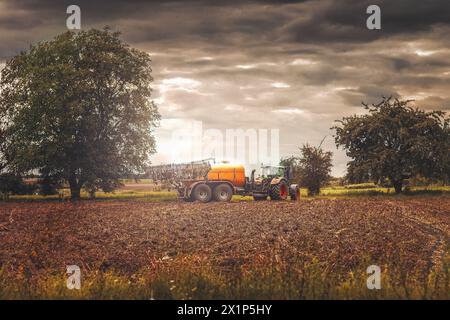 Traktor eines Landwirts auf dem Feld für die Ernte unter einem trüben Himmel Stockfoto