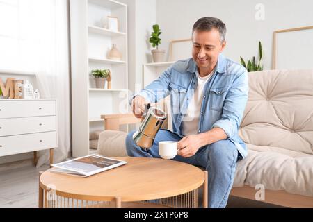 Reifer Mann, der Espresso aus der Geysir-Kaffeemaschine in die Tasse zu Hause gießt Stockfoto