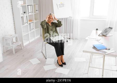 Reife Geschäftsfrau mit Laptop, die im Büro die Wechseljahre erlebt Stockfoto
