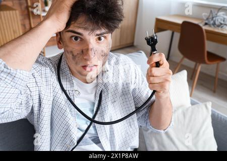 Ein junger Mann mit Verbrennungsgesicht und Stecker zu Hause, Nahaufnahme Stockfoto