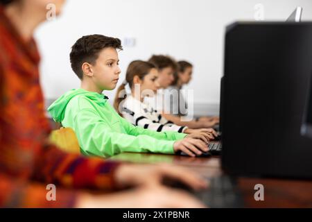 Konzentriert zwischen Jungen, die mit Klassenkameraden im Computerlabor studieren Stockfoto