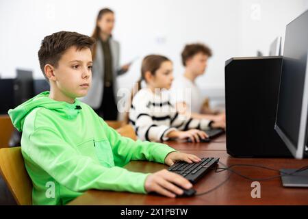 Konzentriert zwischen Jungen, die mit Klassenkameraden im Computerlabor studieren Stockfoto