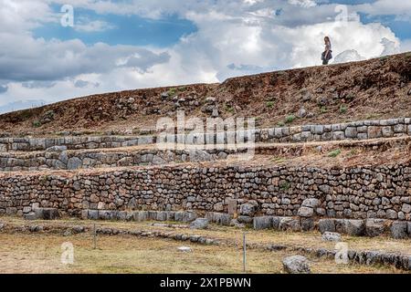 CUSCO, PERU - 1. OKTOBER 2023: Eine anonyme Frau spaziert auf der Spitze der Mauern der alten Inka-Festung in Sacsayhuaman bei Cusco, Peru. Stockfoto
