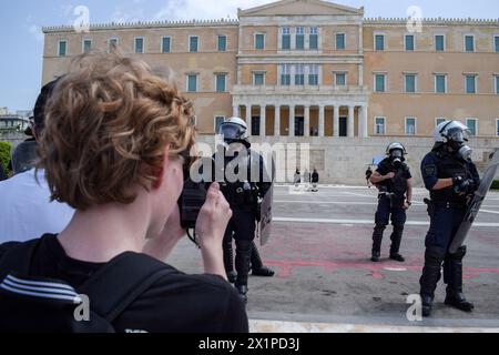 Athen, Griechenland. 17. April 2024. Touristen bestehen darauf, Fotos vom Wachwechsel auf dem Syntagma-Platz zu machen, trotz der starken Präsenz der Polizei gegen Aufstände aufgrund der Protestmärsche. Tausende von Menschen gingen während eines 24-stündigen landesweiten Streiks auf die Straßen der griechischen Hauptstadt und verurteilten die steigende Armut und die rasante Inflation, die Lohnerhöhungen und die Wiederherstellung von Tarifverträgen forderte. Quelle: Dimitris Aspiotis/Alamy Live News Stockfoto