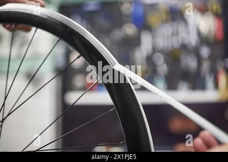 Unbekannte Person, die an einem Fahrradgemälde arbeitet. Zeit zum Entfernen des Abdeckbands der Radfelge. Nahaufnahme der Hände. Stockfoto