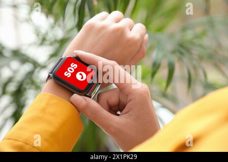 Frau mit SOS-Funktion bei Smartwatch drinnen, Nahaufnahme Stockfoto