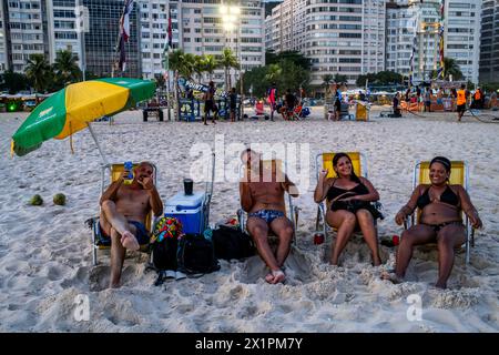 Einheimische sitzen am Copacabana Beach bei Sonnenuntergang, Rio de Janeiro, Bundesstaat Rio de Janeiro, Brasilien. Stockfoto