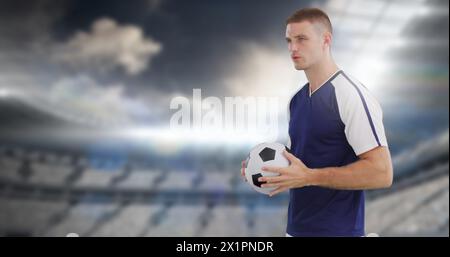 Mann, der Fußball hält, steht im Stadion Stockfoto