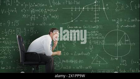 Der kaukasische Junge denkt über mathematische Gleichungen auf der Tafel nach Stockfoto