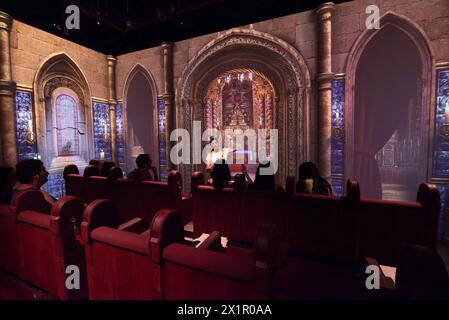 ERDBEBEN-Museum in Lissabon, Centro do Terramoto de Lisboa, Belém, Lissabon, Portugal. Eine Gruppe von Besuchern sitzt in den Bänken, während eine Videoprojektion des Inneren der Kirche von São Nicolau an den Wänden des Museums projiziert wird. Ein Museumsmitarbeiter beschreibt die Erfahrung des Beben, bevor eine Simulation stattfindet, in der der Boden wackelt und das Feuer und der Zusammenbruch des Kirchengebäudes auf Video dargestellt wird. Das 1.800 Quadratmeter große Museum, das dem großen Erdbeben von Lissabon von 1755 gewidmet ist, wurde im April 2022 für die Öffentlichkeit eröffnet. Stockfoto
