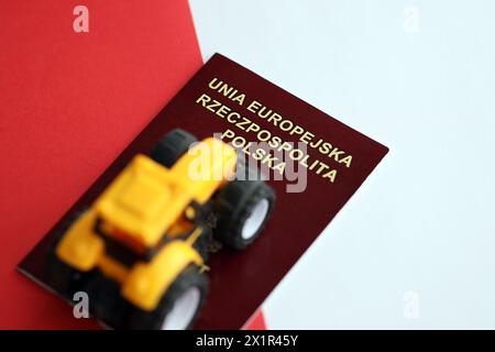 Roter polnischer Pass und gelber Traktor auf glatter rot-weißer Flagge von Polen Nahaufnahme Stockfoto